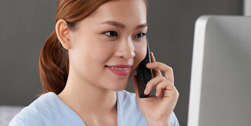 Asian nurse on the phone looking at her computer