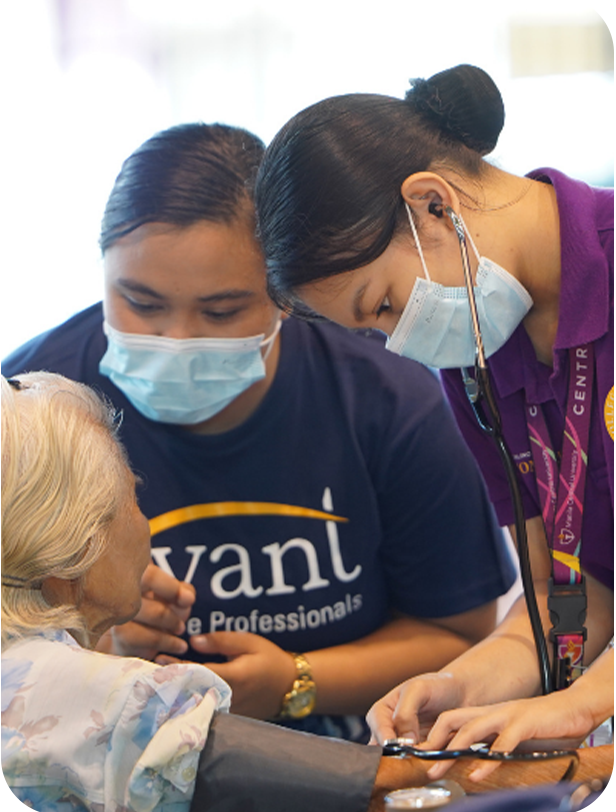 Two healthcare professionals, wearing masks, examine an elderly patient's arm during a medical check-up.