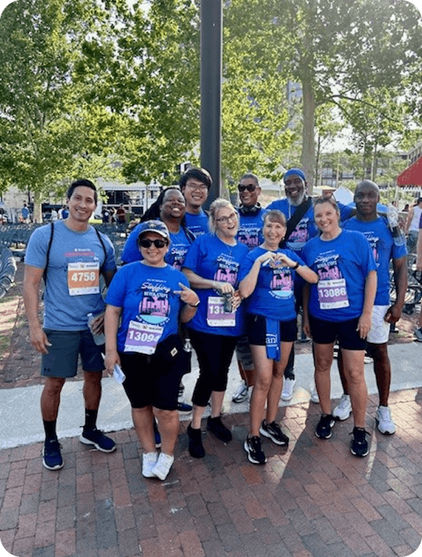 Group of diverse people in matching blue shirts participating in a charity walk or run event outdoors.