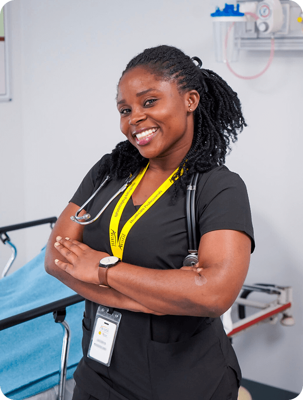A smiling nurse with a stethoscope around her neck, wearing black scrubs and a yellow lanyard, standing confidently in a