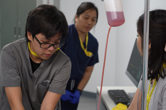 Medical professionals assist a patient with a blood transfusion in a clinical setting.
