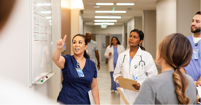 Healthcare professionals in a hospital corridor discussing patient care and listening to a presentation.