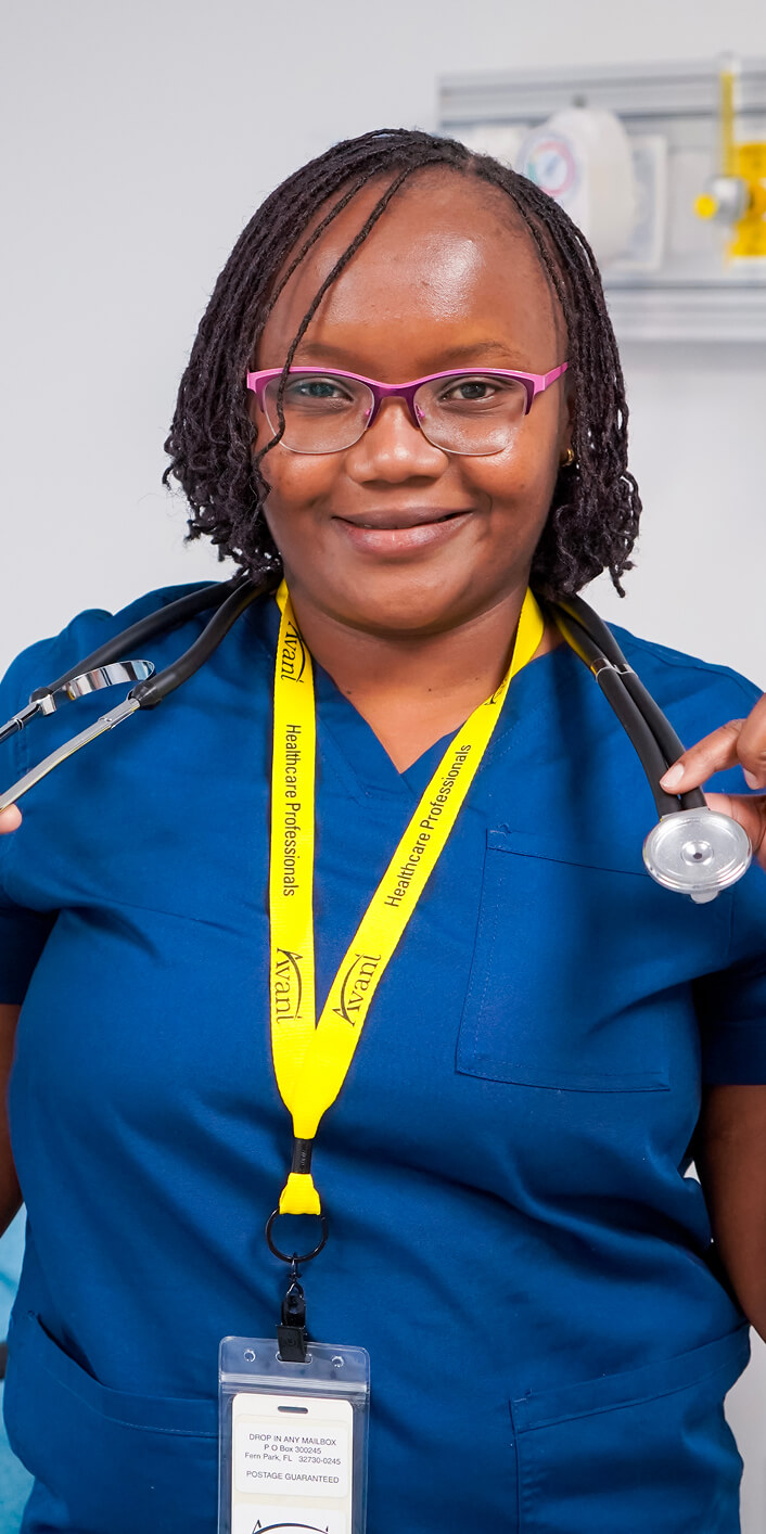 Kenyan healthcare professional wearing blue scrubs, pink glasses, and a yellow lanyard with a stethoscope.