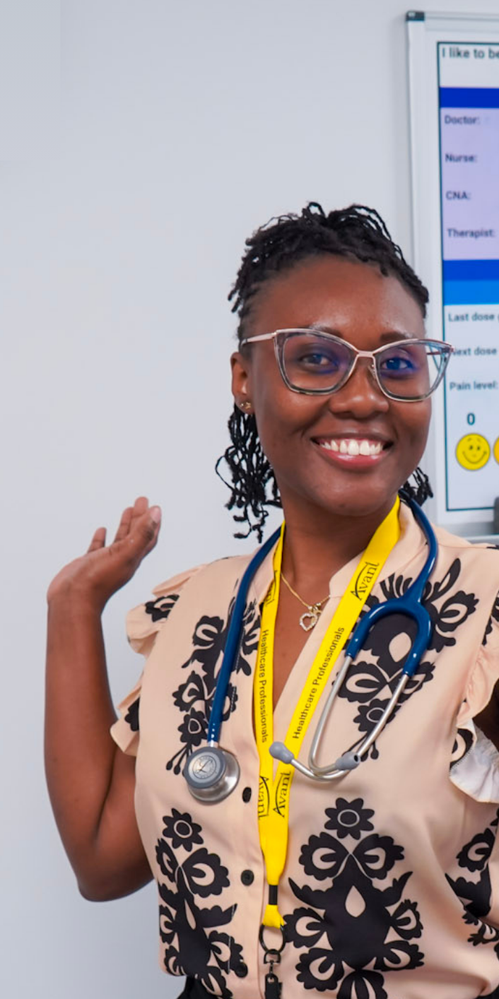 A smiling healthcare professional with glasses and a stethoscope around her neck, wearing a beige and black floral uniform.