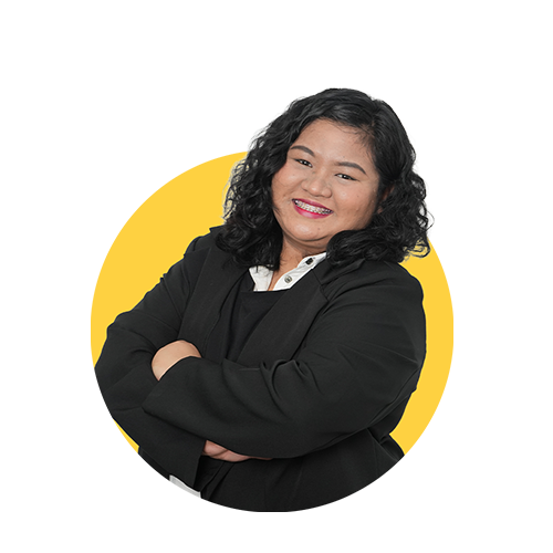 A confident woman with curly black hair, smiling and crossing her arms, wearing a black blazer against a yellow background.