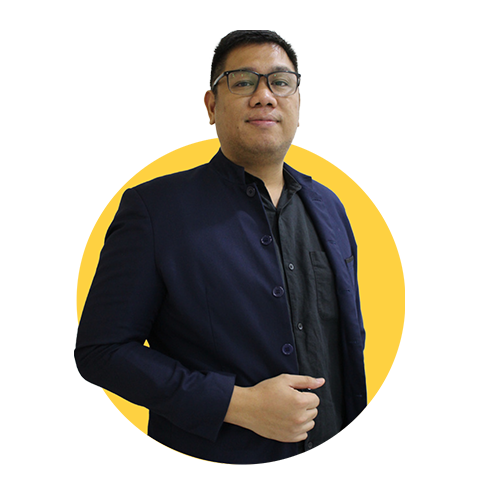 Richard Fran, a man with short black hair and glasses, wears a dark blazer and black shirt, standing confidently against a