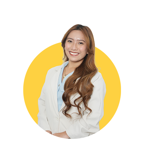 A smiling woman with long, wavy hair wearing a white coat stands against a yellow background.