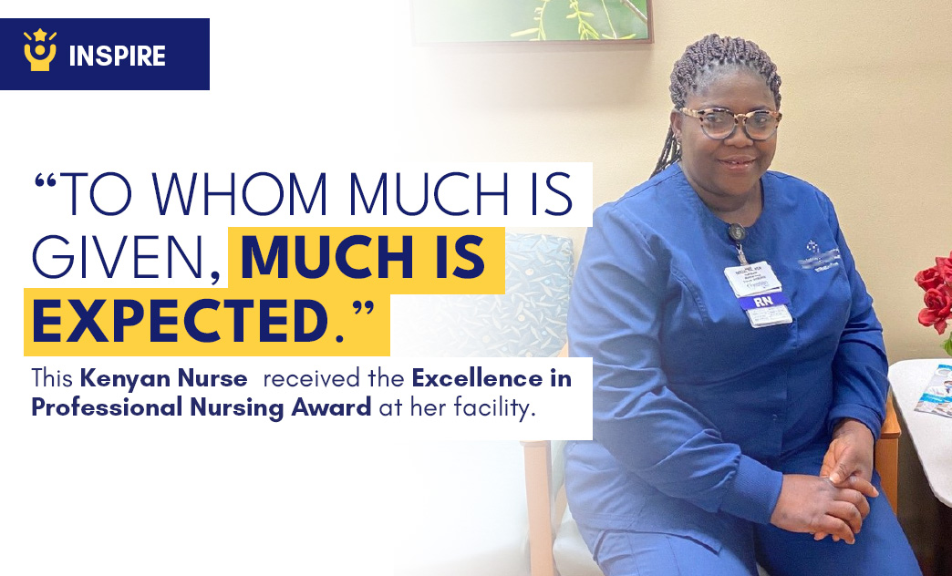 A Kenyan nurse in blue scrubs and glasses sits with hands clasped, smiling in a healthcare setting.