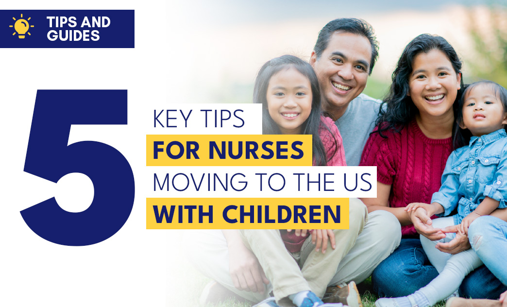 A smiling family of four sitting outdoors on grass, with two young girls and parents, enjoying a sunny day together.
